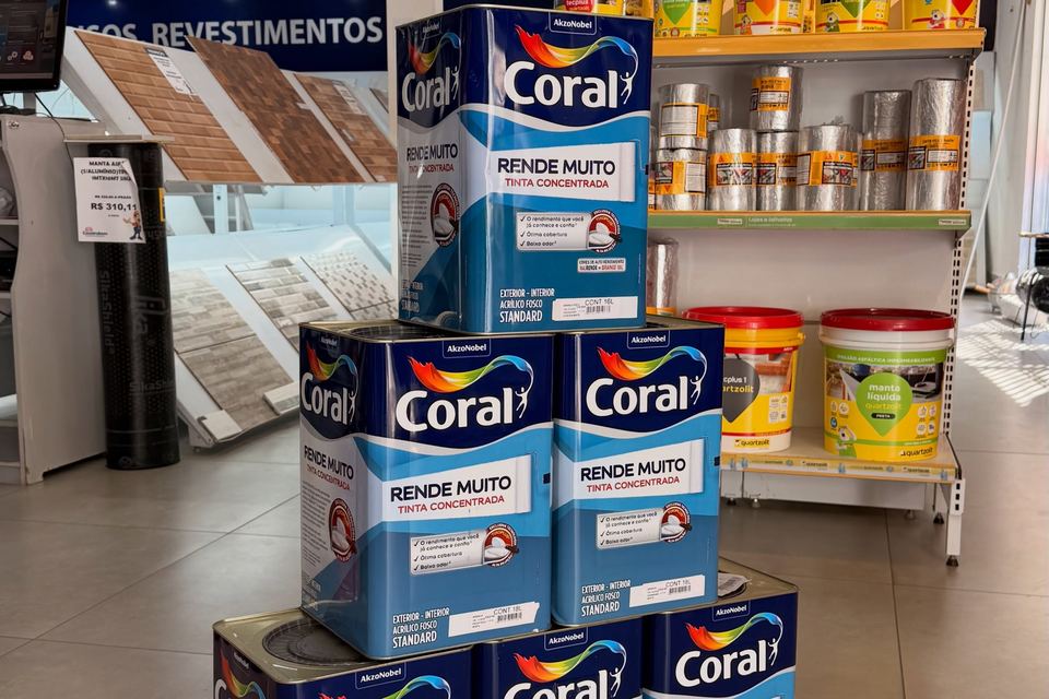 Pilha de latas de tinta Coral e prateleiras de tintas na loja